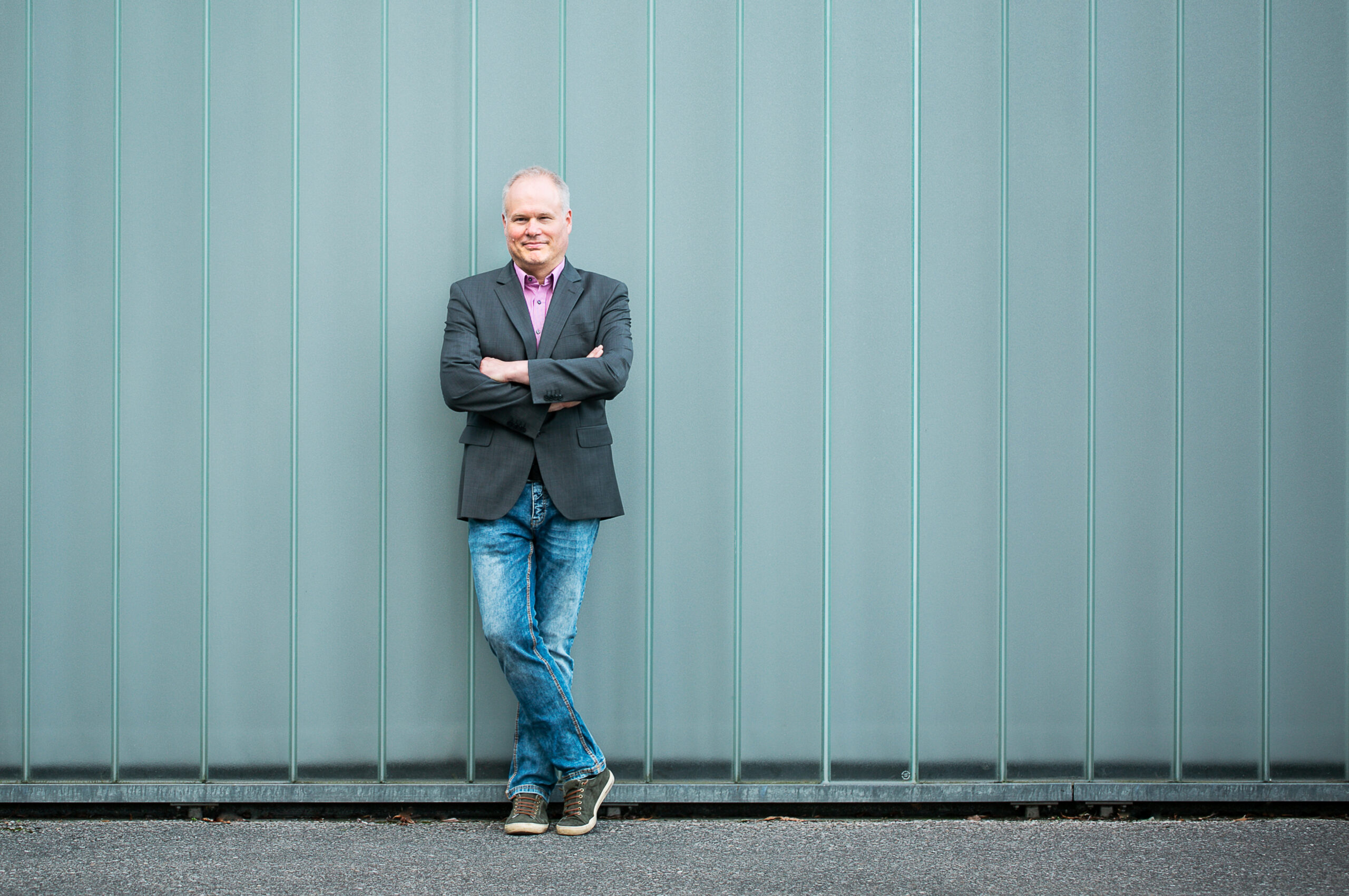 Männerportrait outdoor, im Hintergrund eine türkisfarbene Plexiglaswand