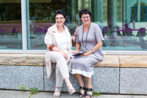 Frauenportrait outdoor, zwei Frauen sitzen vor einem Café