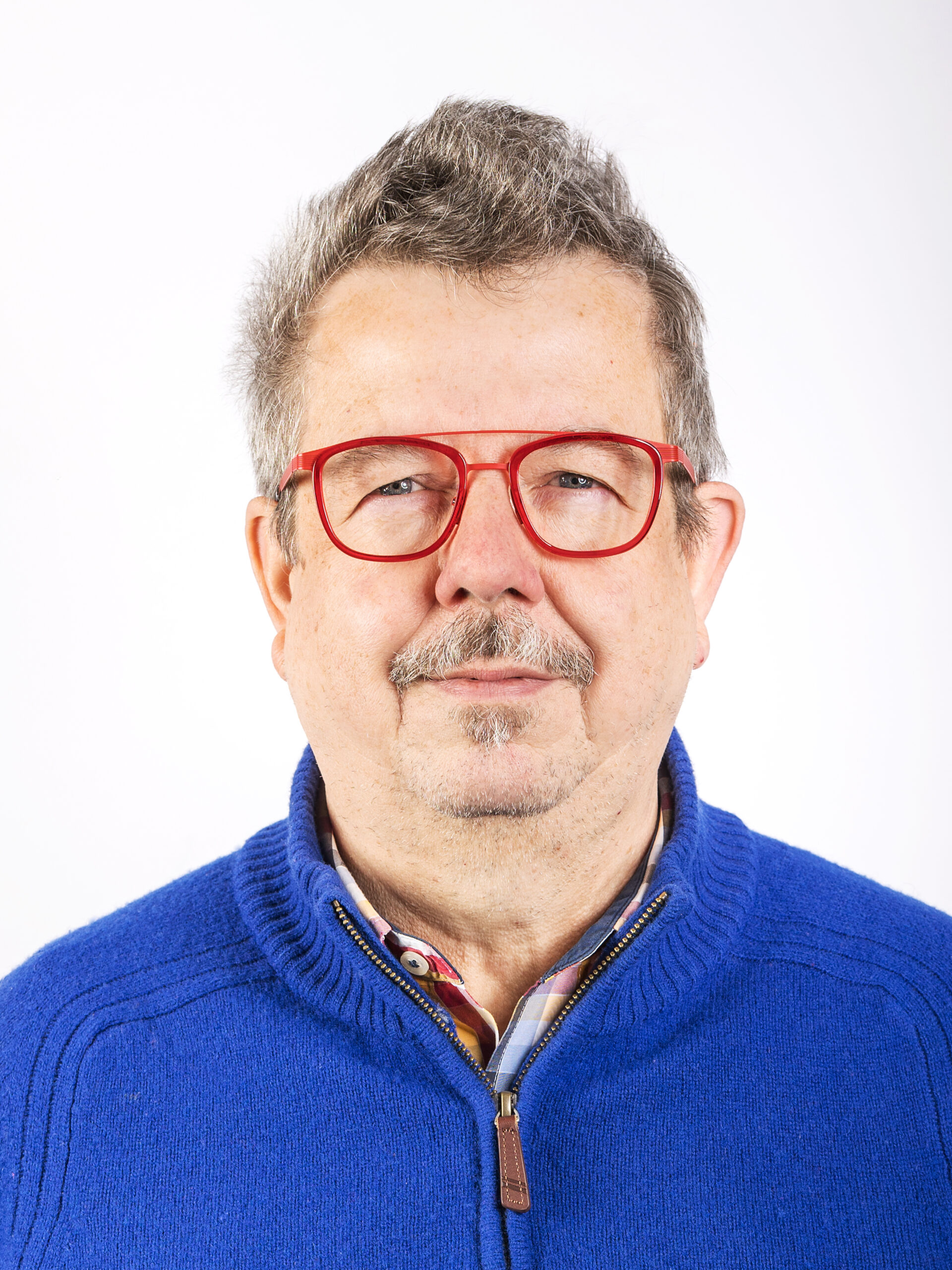 Studio-Portrait Mann mit blauem Pullover und roter Brille