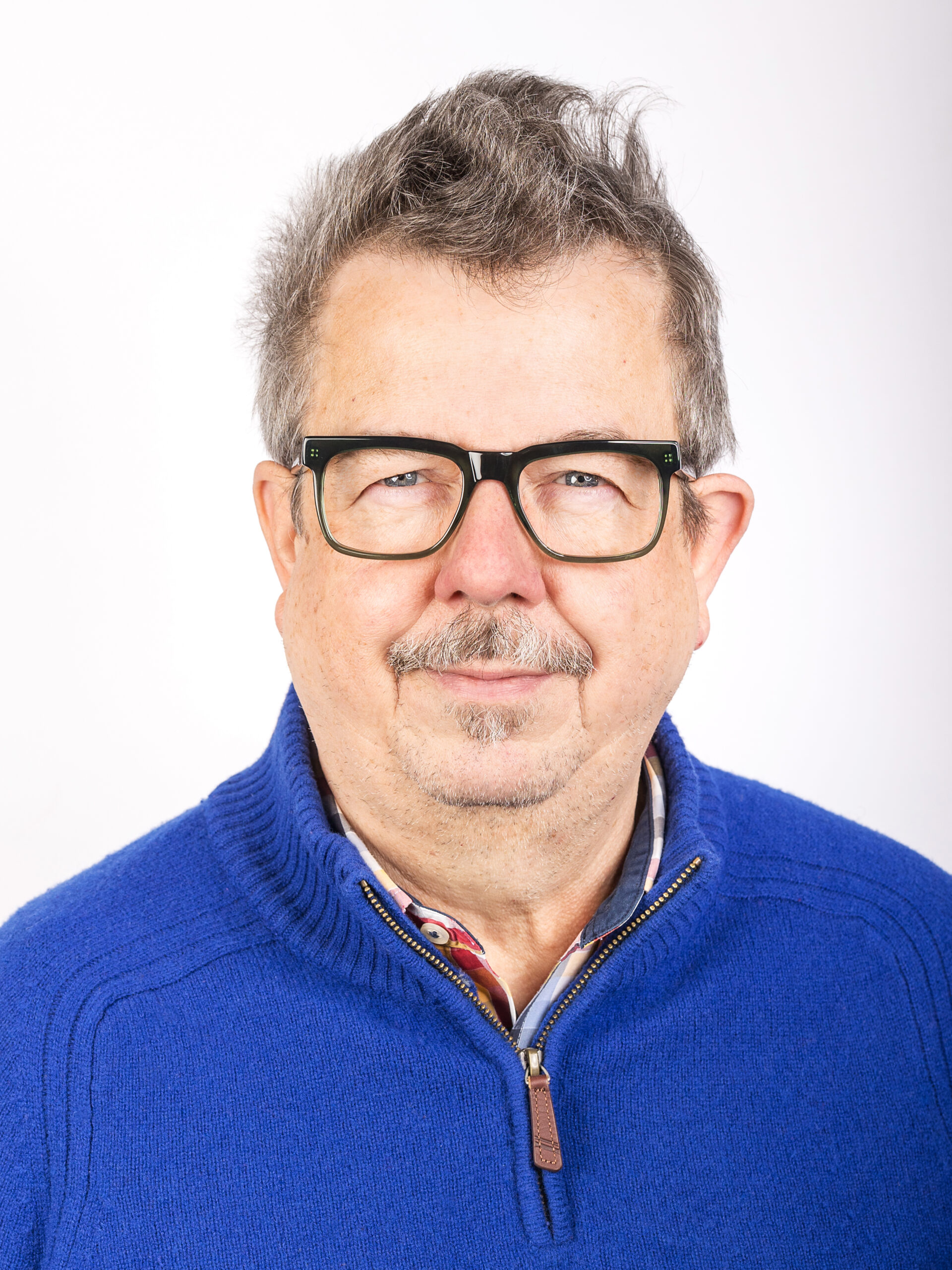 Studio-Portrait Mann mit blauem Pullover und schwarzer Brille