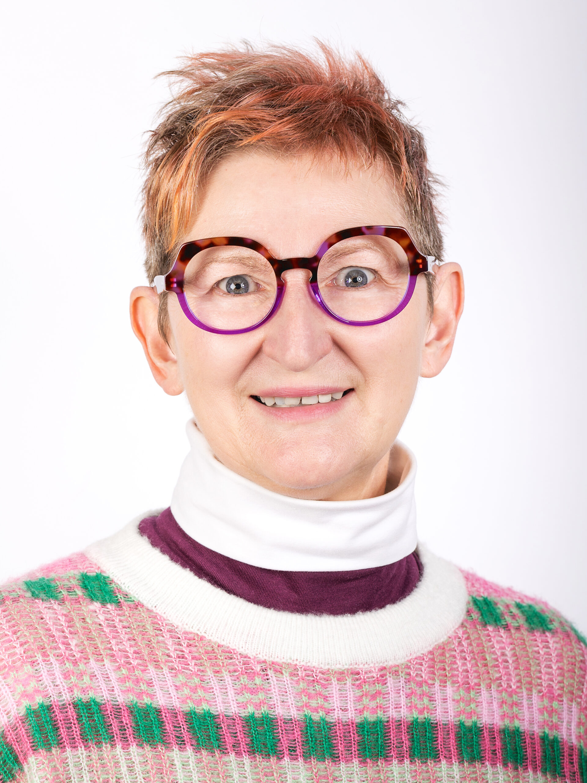 Studio-Portrait Frau mit pink-weiss-grünem Pullover und großer, braun-lila Brille