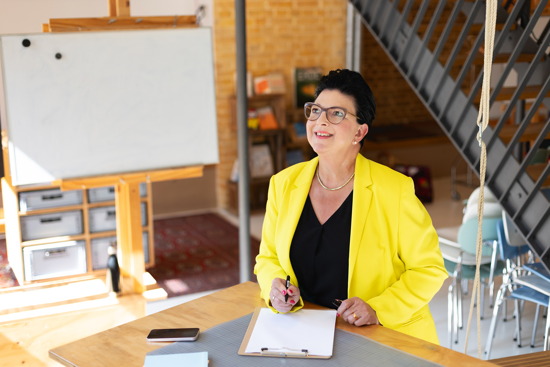 Frauen-Portrait indoor, Frau steht am Schreibtisch und denkt nach