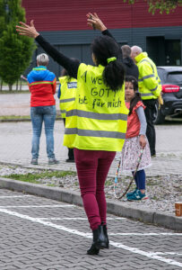 Helferin mit Signalkleidung und Aufschrift "Gott ist für mich"