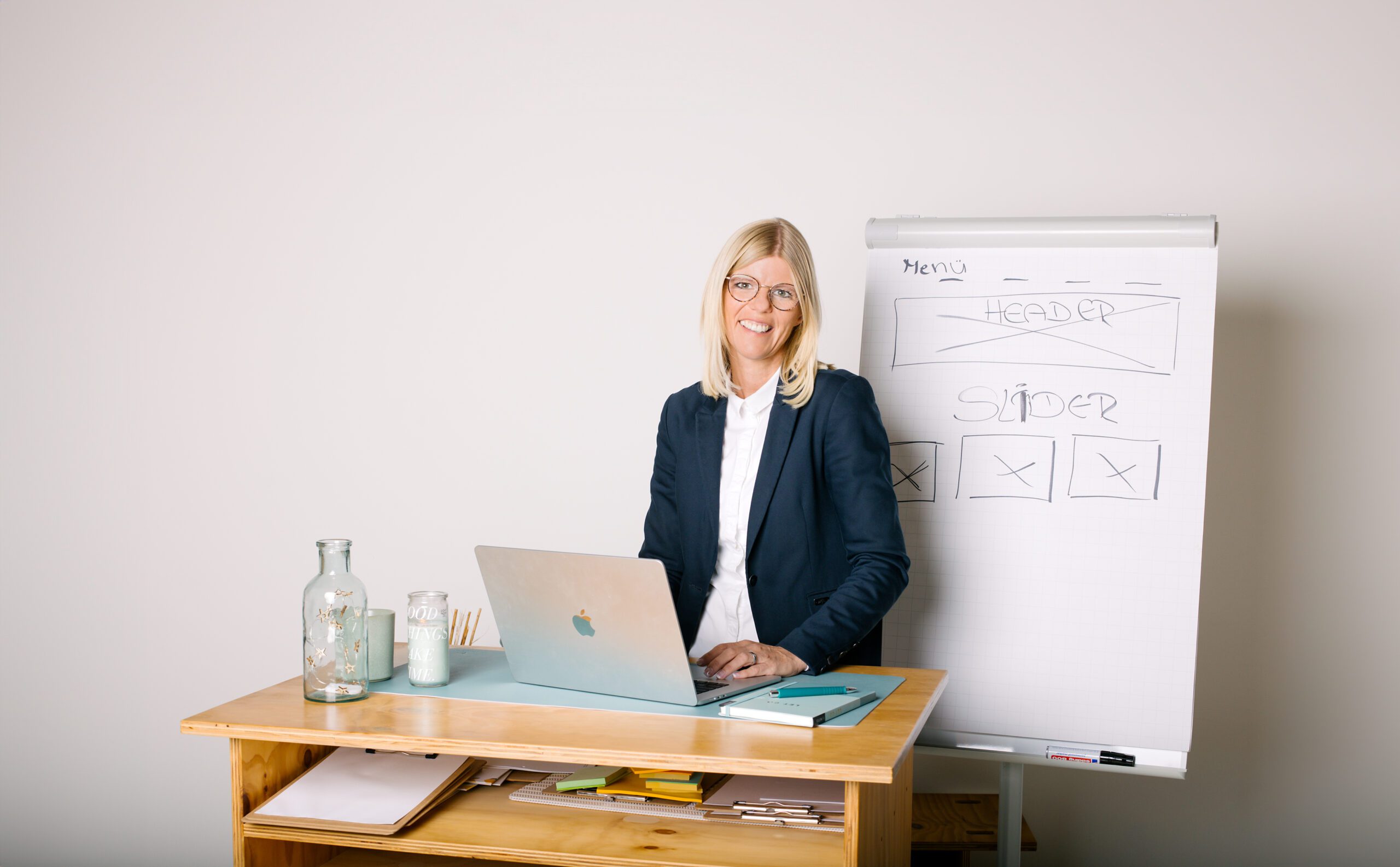 Personal Branding Shooting - blonde Frau am Laptop, im Hintergrund Flipchart