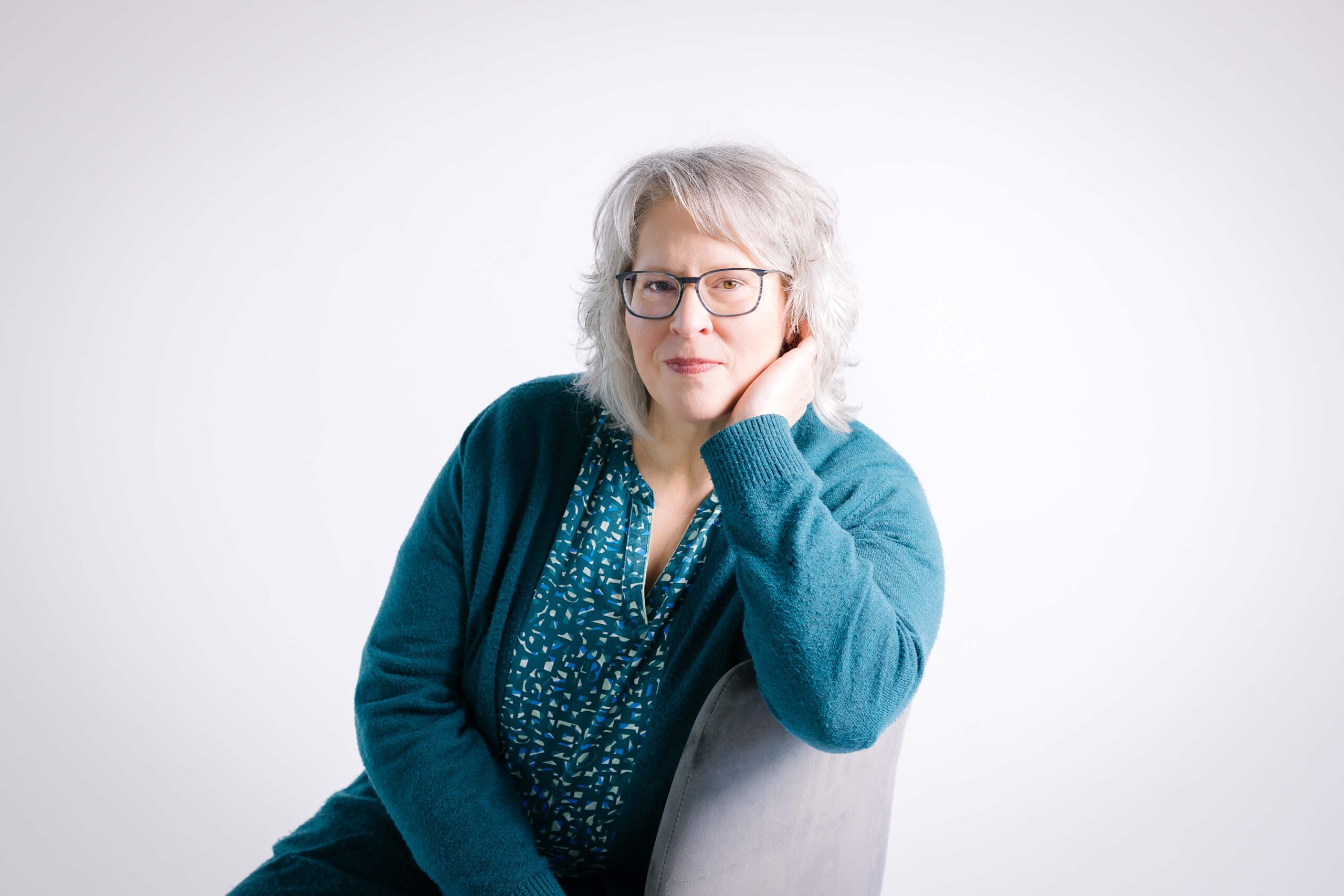 weißblonde Frau mit Brille lässig sitzend