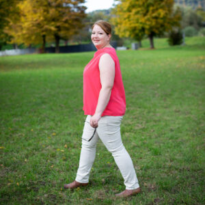 Businessfotografie Esslingen – Frau in lässiger Kleidung mit Sonnenbrille in der Hand läuft über eine Wiese in einem Park